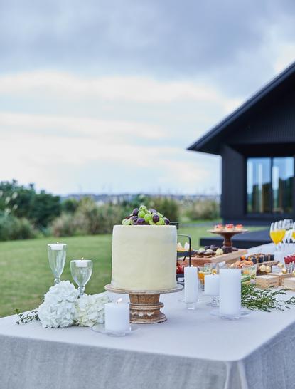 アマネムリゾートの広大な景色を望むテラスに設えられた、白いテーブルクロスと装花のウェディング祝いのセットアップ。