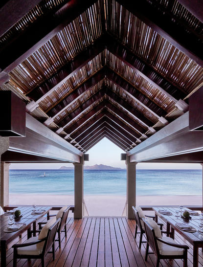 Dining pavilion at Amanpulo with wooden vaulted ceiling framing turquoise waters and white sand beach beyond.