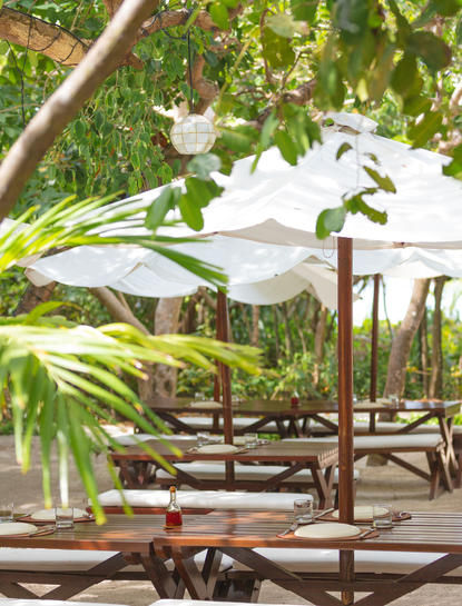 Amanpulo 리조트의 피크닉 그로브에서 우산과 나무 테이블이 있는 야외 식사 공간.