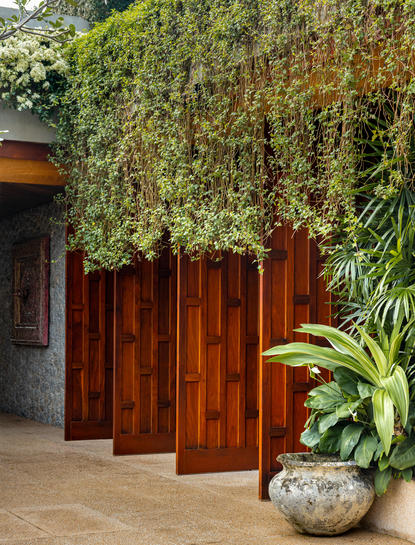 安缦璞瑞度假村入口处，木制屏风前种植着绿色藤蔓植物。