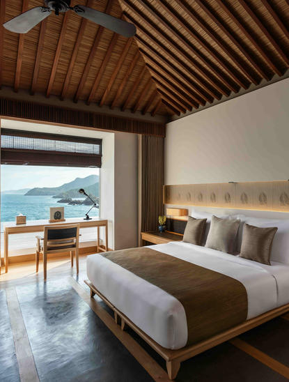 アマノイ リゾートのオーシャンプール レジデンスの主寝室。木製天井、海の眺望、モダンなベッドが特徴。