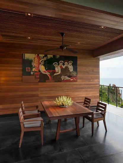 Dining area at Amanoi resort with wooden table, chairs, and ceiling detail overlooking coastal landscape.