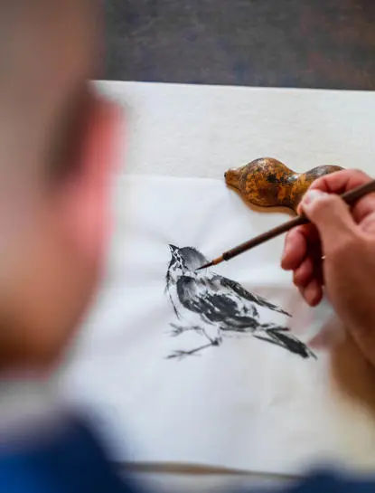 Artiste peignant un oiseau à l'encre lors d'un atelier au resort Aman Kyoto.