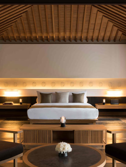 Amanoi pavilion bedroom with teak ceiling, floating bed with integrated lighting, and built-in wooden shelving.