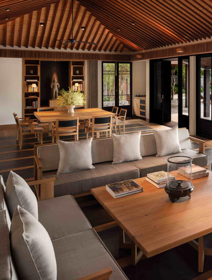 Amanoi lounge with wooden ceiling, dining table and seating areas overlooking natural landscape.