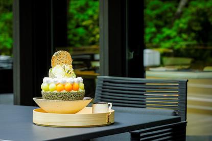 Tiered matcha cake with gold leaf on black table at Aman Kyoto resort.