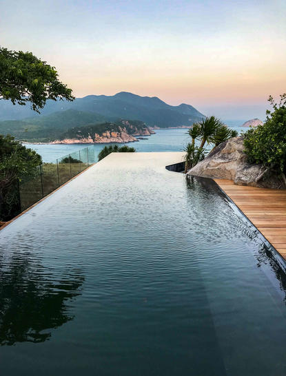 安缦诺怡度假村的海景泳池，俯瞰平静海湾和远处山峦。