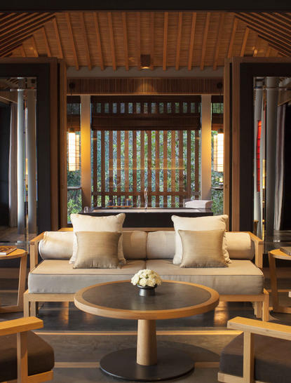 Amanoi resort の木造パビリオン内部。天井の高い空間に、ライトベージュのソファと木製テーブルが配置され、落ち着きのある和のデザイン。
