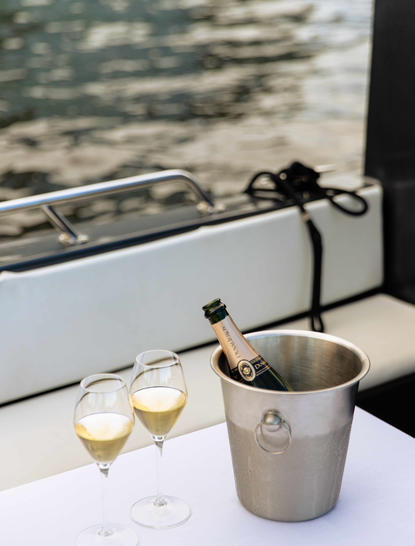 Dwy wydryn champagne a pwyced arian ar bwrdd gwyn gyda golygfeydd dŵr yn Aman Tokyo.