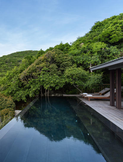 Ocean pool at Amanoi overlooking forested hillside and still waters.
