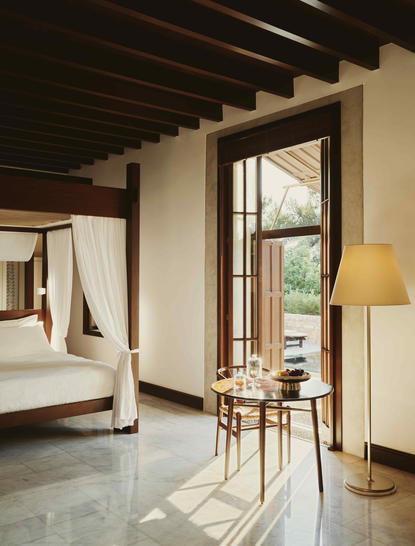 Garden view pavilion room at Amanruya with four-poster bed and seating area opening to terrace.