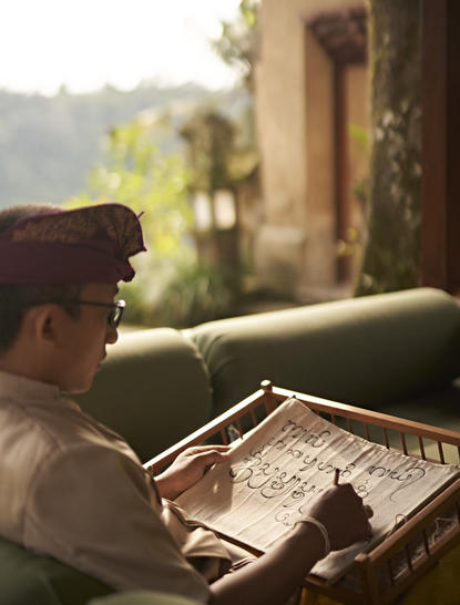 Amandari resort में Balinese script class के दौरान Aksara Bali सीखते हुए अतिथि।