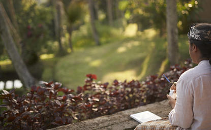 Painting class participant at Amandari resort, Indonesia, holding brush and palette whilst seated outdoors.