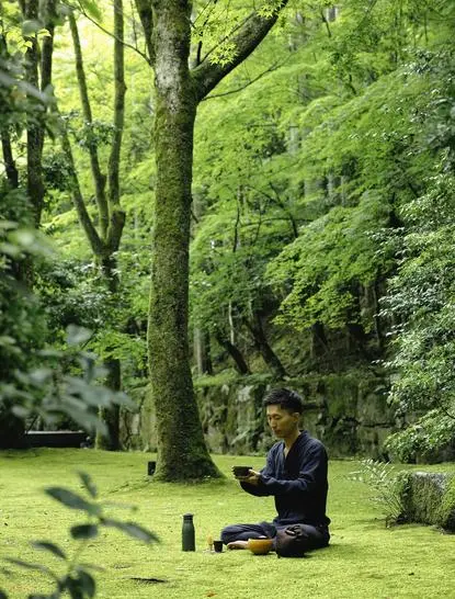 Woman sitting beneath tall tree in lush green garden at Aman Kyoto, enjoying open-air tea ceremony.