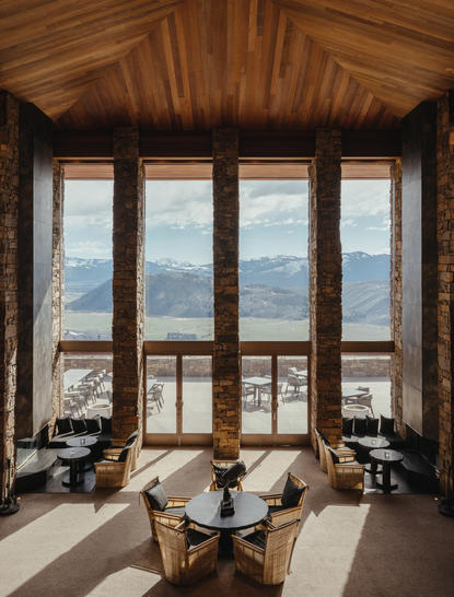Grand staircase lobby at Amangani with wooden vaulted ceiling and floor-to-ceiling windows overlooking mountain landscape.