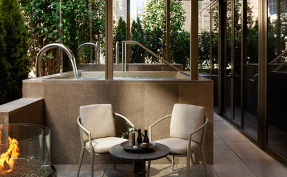 Terrasse du spa avec baignoires en pierre et sièges confortables à Aman New York.