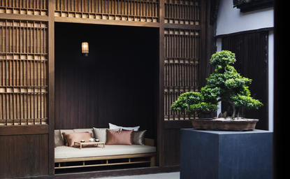 Amanfayun lounge with bonsai tree display and cushioned seating alcove.