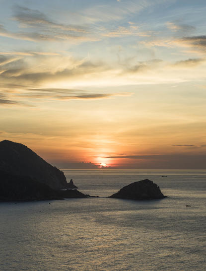 Sunrise over the sea at Amanoi, with silhouetted islands beneath golden sky.