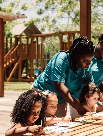 Children playing on a wooden deck at Amanyara with a playground structure visible in the background.