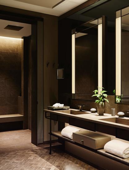Salle de bains de la Junior Suite Fifth Avenue à Aman New York, avec miroir éclairé et finitions sombres élégantes.