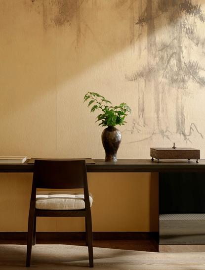 安缦纽约酒店的套房内，简约木质书桌上摆放着黑色花瓶和绿色植物。