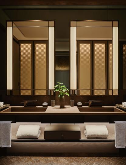 Serene seating area at Aman New York with paired mirror panels and soft green plant accent on dark surface.