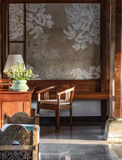 Amandari resort interior with wooden desk, chair, and potted white flowers beside a decorative window panel.