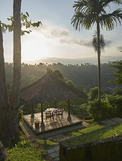 Private dining pavilion at sunset, Amanwana, with verdant valley views and palm trees.