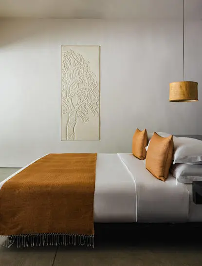 Principal bedroom at Amansara with wood-framed bed and ochre accents.