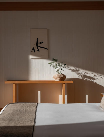 アマン東京のホテルの客室、木製の低いサイドボードと壁に掛かった墨絵が特徴。