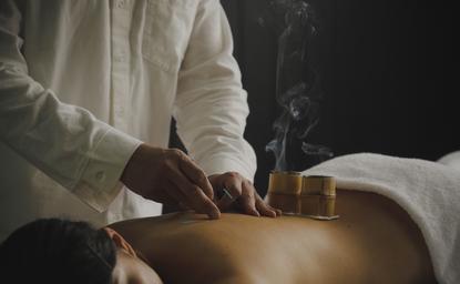 アマン京都のリゾートで、鍼灸治療を受ける人の手元。温かみのある照明に包まれた穏やかな施術風景。