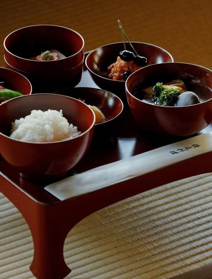 Shojin ryori kaiseki course at Aman Kyoto resort, featuring bowls of rice, vegetables and broths arranged on a wooden tray.