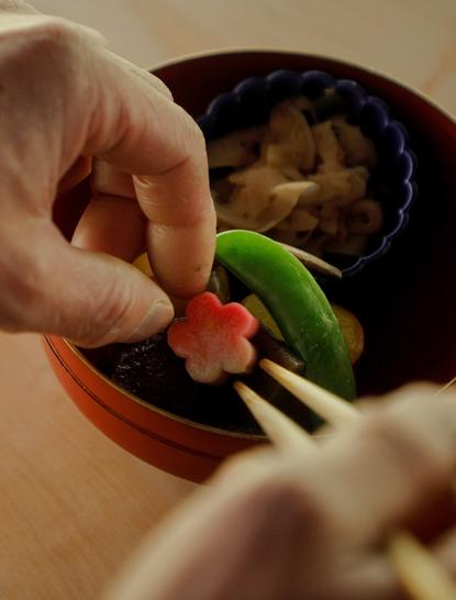Hands preparing shojin Buddhist vegetarian cuisine at Aman Kyoto resort, featuring fresh vegetables in a traditional bowl.