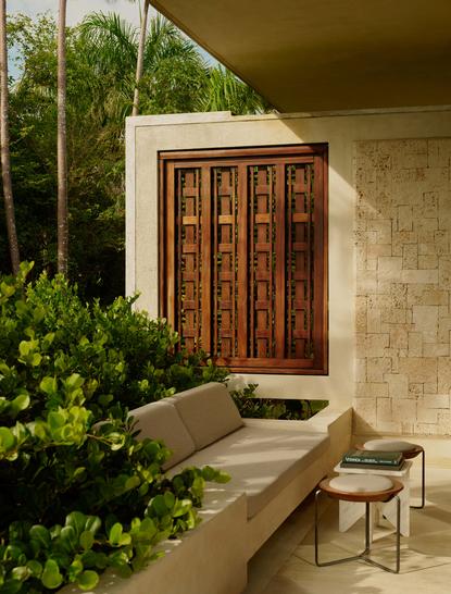 Casita entrance at Amanera resort with wooden door, stone walls, and shaded seating area surrounded by tropical greenery.