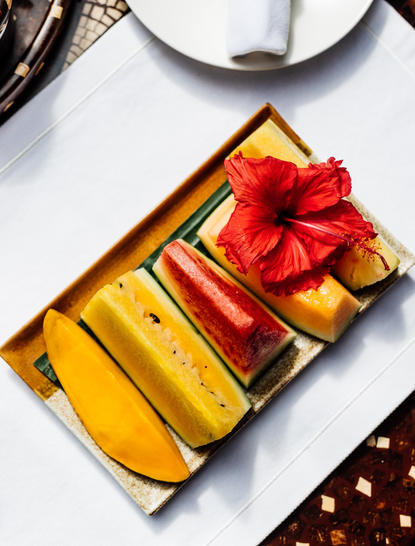Colazione ad Amanpulo: vassoi dorati con frutta fresca e fiocco rosso al resort.
