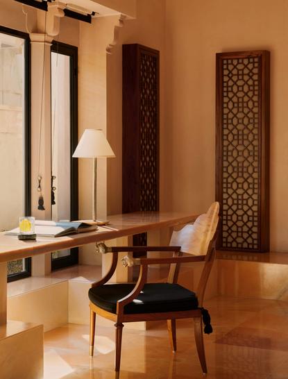 Pool Pavilion dressing room at Amanbagh with carved wooden screens and mid-century chair.