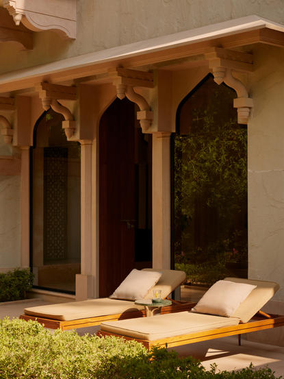 Garden Haveli Suite with stone archways, cushioned daybed, and verdant garden at Amanbagh.