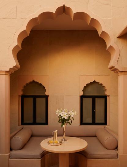 Courtyard haveli suite at Amanbagh with arched alcove, two windows and central table with flowers.