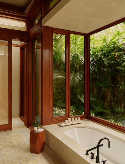 Salle de bains avec baignoire et larges fenêtres surplombant la végétation, à Amanera resort.