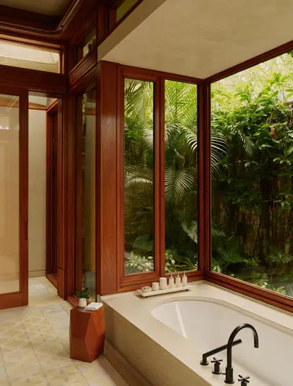 Bathroom with soaking tub and large windows overlooking garden at Amanera.