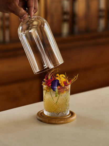 Cocktail siendo vertido en un vaso con hielo y flores en Amanera resort.