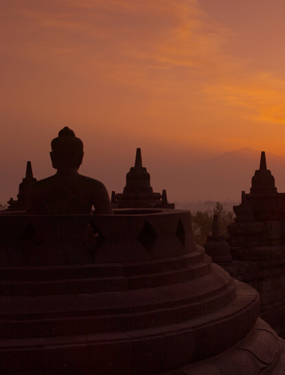 Borobudur temple silhouetted against an orange dawn sky in Indonesia, near Amansara.
