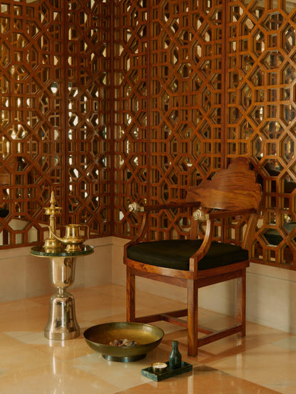 Spa treatment room at Amanbagh with terracotta mosaic wall, wooden chair and aromatherapy bottles.