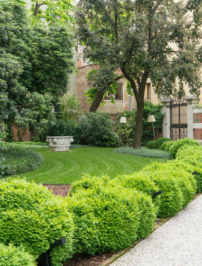 Verdant garden with manicured hedges and mature trees at Amanpulo resort.