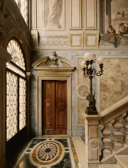Escalier classique à Aman Venice, avec murs en marbre clair et détails architecturaux élégants.