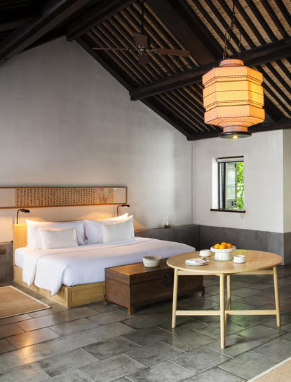 Amanfayun village room with wooden beamed ceiling, dressed bed, and lantern-style pendant light.