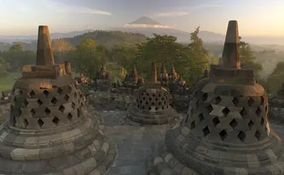 婆罗浮屠佛教寺庙建筑群在日出时分笼罩在晨雾中，安缦齐和度假村景观。