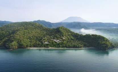 Vista aérea de la península boscosa de Amankila resort con aguas turquesas de Indonesia.