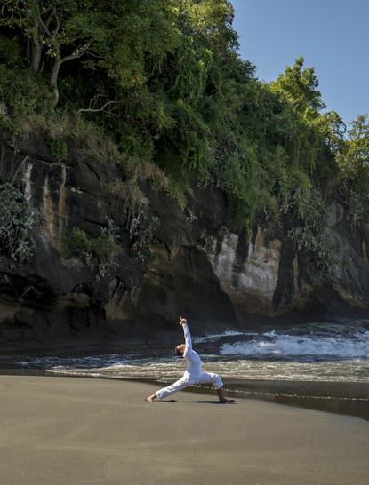 Persona practising yoga on a secluded beach at Amankila resort, Indonesia.
