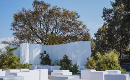 Outdoor dining pavilion at Amandayan with white architectural framing overlooking verdant gardens and distant mountains, China.